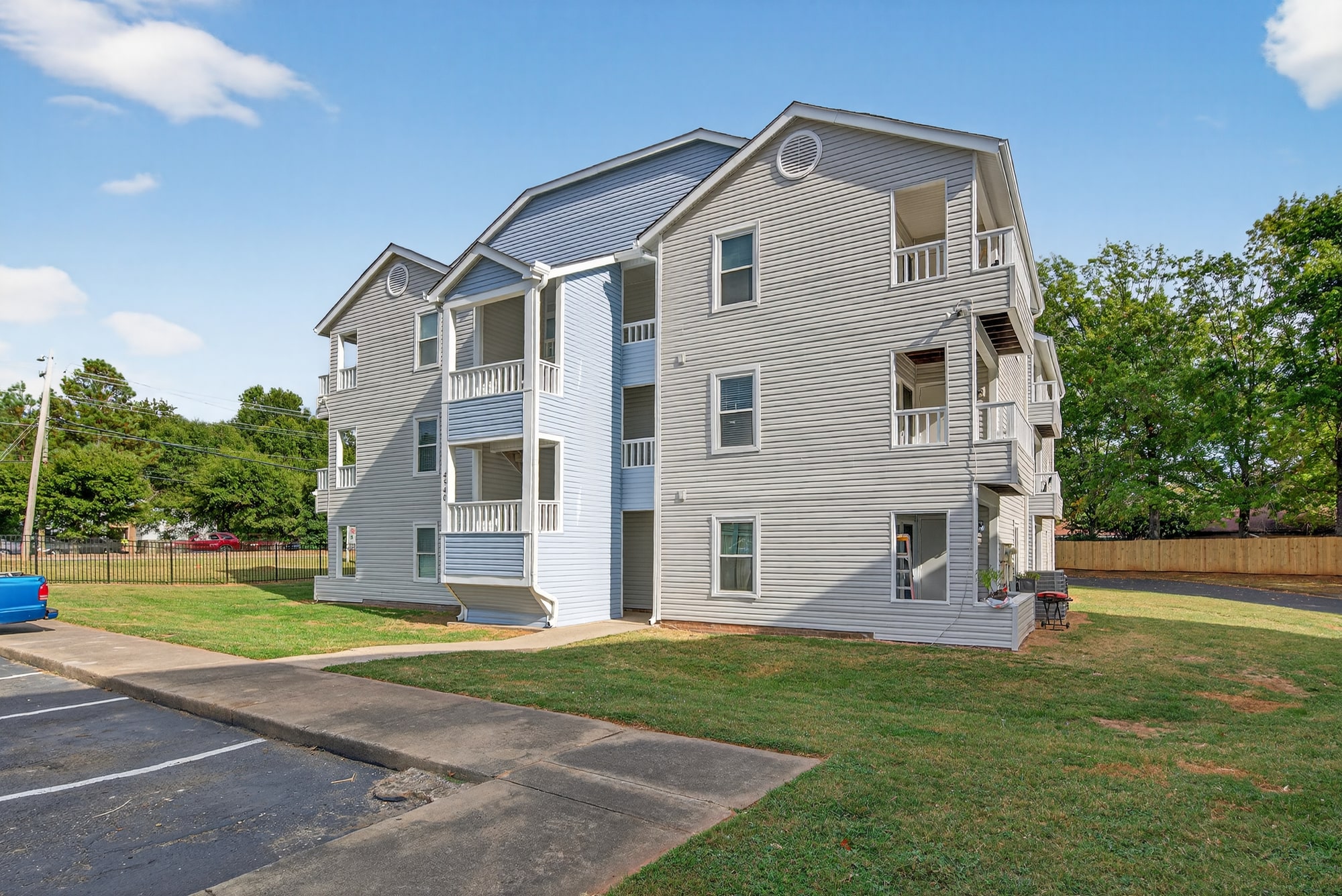 The Grove Apartments building with blue and gray siding, white balconies, and surrounding green space